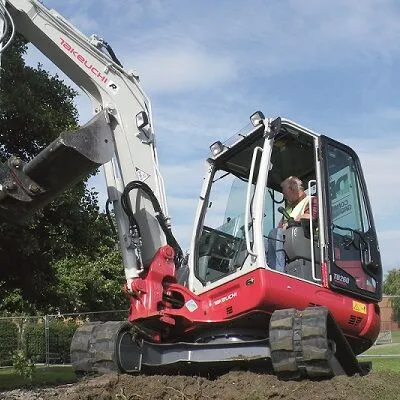 Takeuchi TB260 compact excavator working beside a building