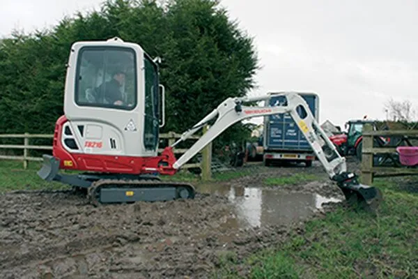 Takeuchi TB216 compact excavator working on muddy groundworks