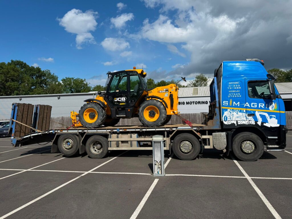 Sims low-loader carrying safety-checked construction equipment for a plant hire account in the UK