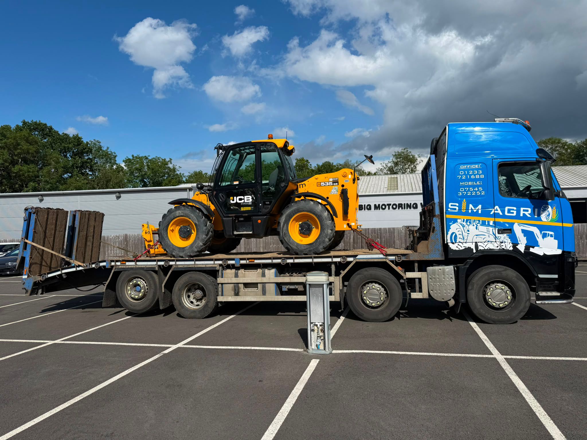 Sims low-loader carrying safety-checked construction equipment for a plant hire account in the UK
