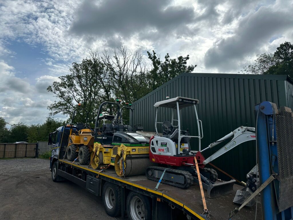 Plant machinery loaded on a trailer beside the Sims depot for the plant hire gallery in the UK
