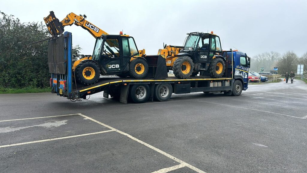 Sims low-loader carrying two yellow backhoe loaders for the excavator hire across the UK