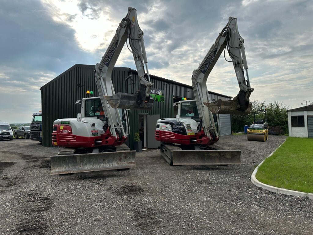 Two compact excavators parked outside the Sims workshop