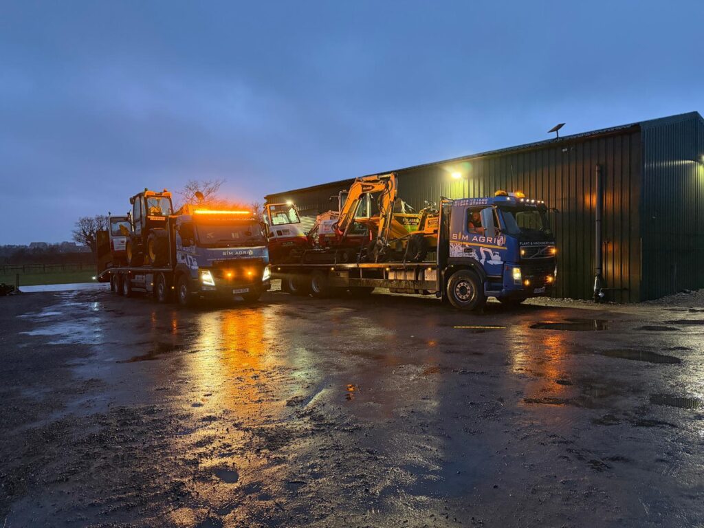 Illuminated Sims plant transport lorries on a wet depot yard