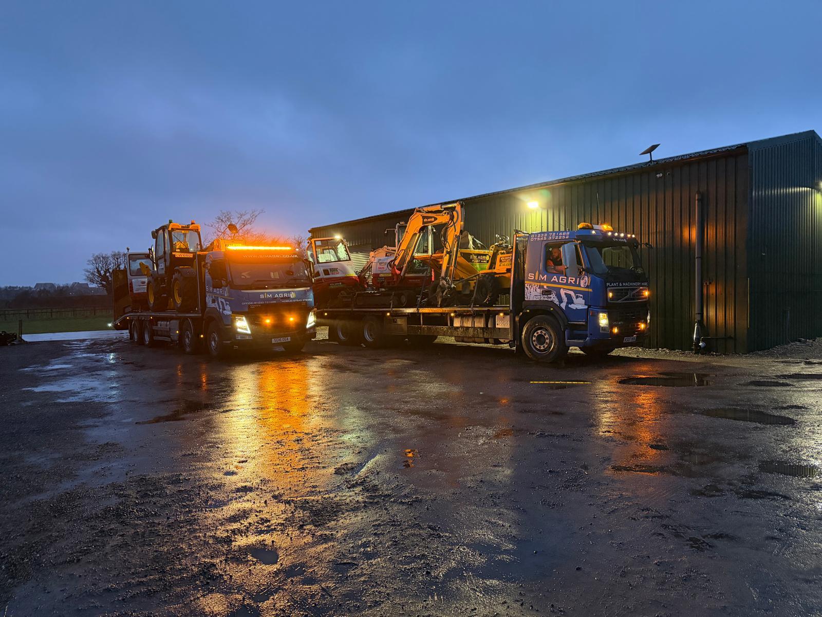 Illuminated Sims plant transport lorries on a wet depot yard