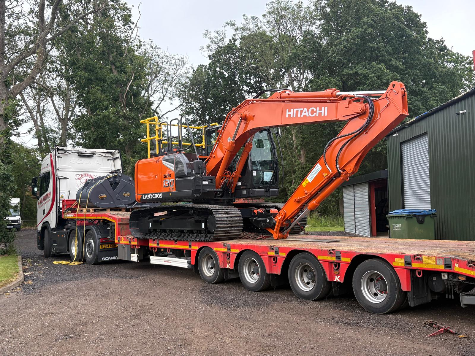 Hitachi excavator on a low-loader for commercial and compliant plant hire services